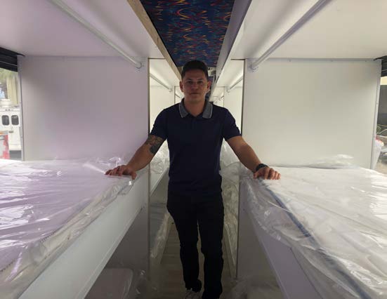 Sleeping pods with bedding and the owner of Heat Customs who participated in the bus conversion.