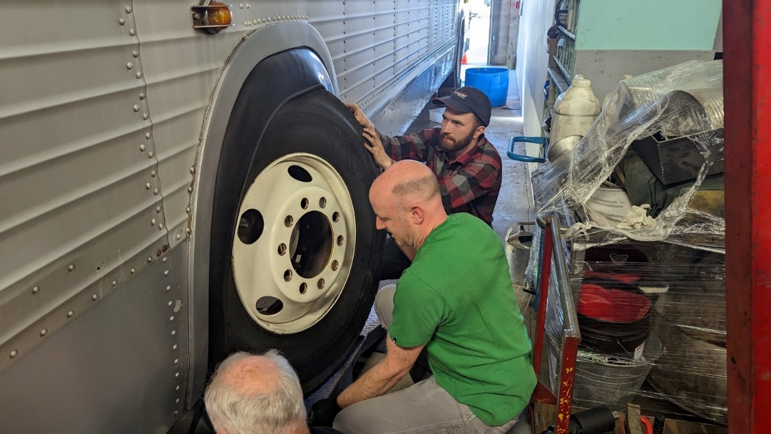 Kyle Little and Jason Sharpe removing the wheel on the new museum Bus.