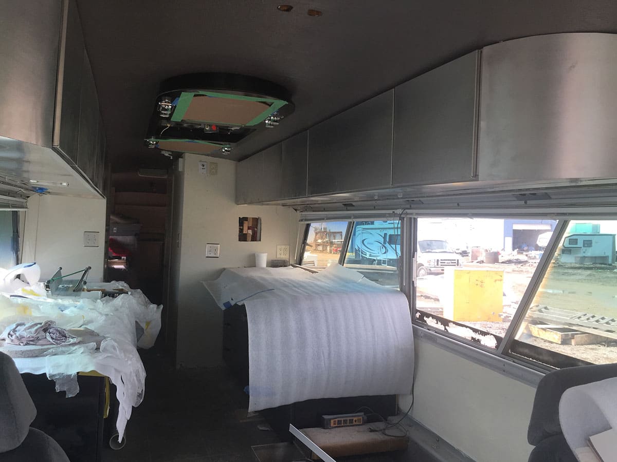This picture shows the interior in mid-build, with cabinetry installed, ceiling infinity mirrors, and the kitchen counter and desk.